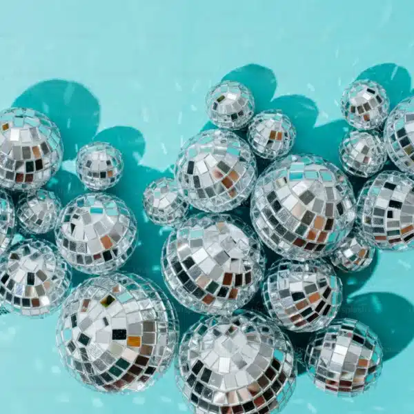 Racimo de bolas de discoteca que reflejan la luz sobre un fondo turquesa.