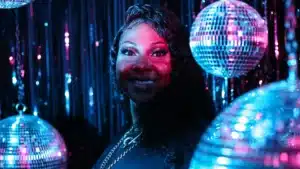 A vibrant scene featuring glittering disco balls under colorful lights with dark curly hair visible.