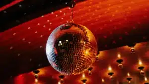 A shining disco ball hanging from the ceiling with reflections of lights.
