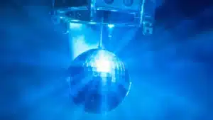 Una bola de discoteca que refleja la luz azul en una habitación llena de humo.
