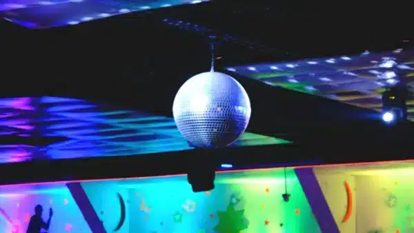 Una bola de discoteca colgando del techo con luces de colores y dibujos en la pared.