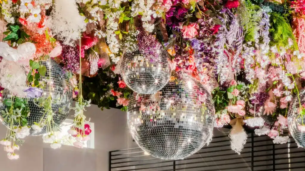 Techo decorado con bolas de discoteca y un surtido de flores de colores.