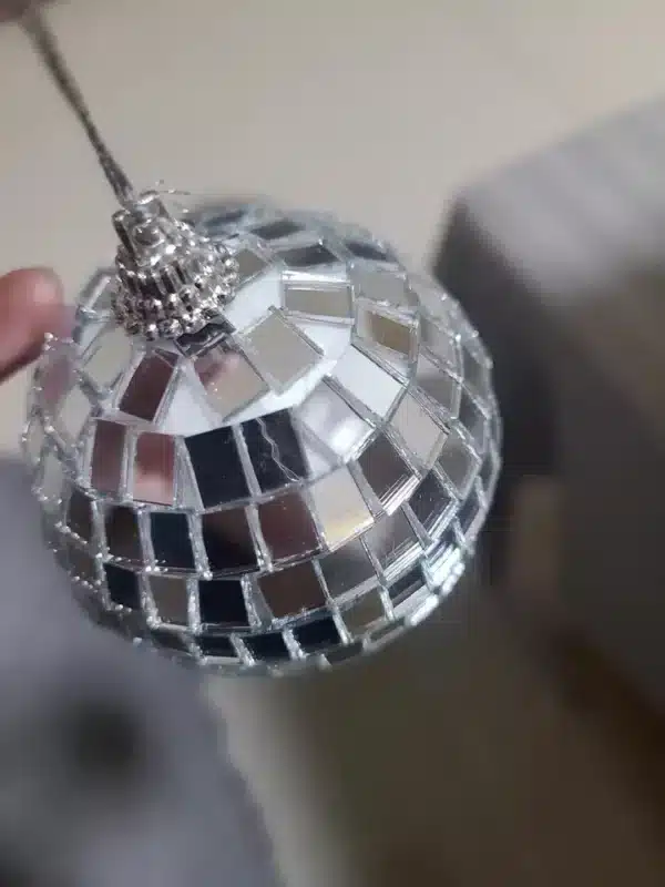 Primer plano de un adorno de bola de discoteca que refleja la luz con pequeños espejos cuadrados.