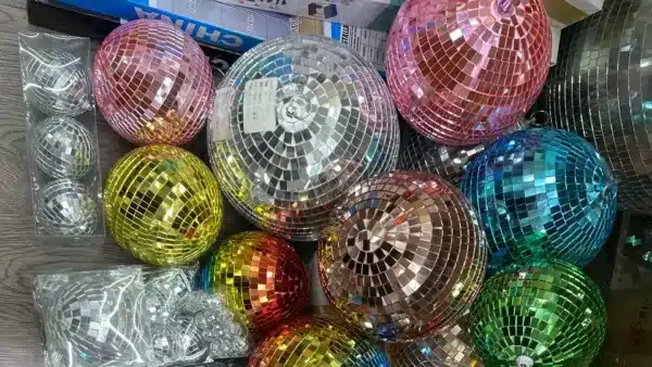 Una colección de coloridas bolas de discoteca de distintos tamaños dispuestas sobre una superficie de madera.