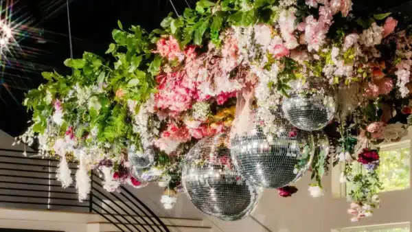 Arreglo floral colgante con bolas de discoteca y exuberante vegetación.