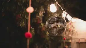 A disco ball hanging outside with string lights and decorative elements, creating a festive atmosphere.