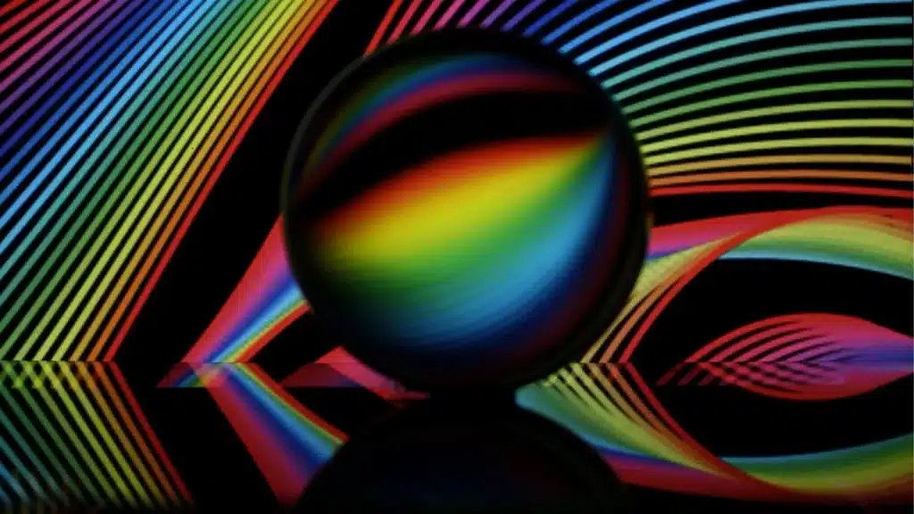 A vibrant image showcasing a sphere reflecting rainbow-colored stripes and waves on a dark background.